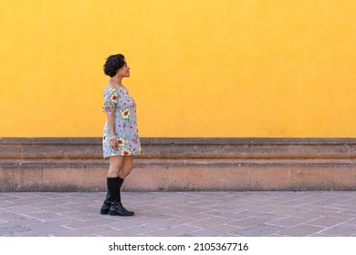 A Mid Adult Afro Mexican Woman Walking In Front Of A Yellow Wall