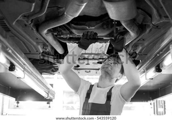 Mid\
adult automobile mechanic repairing car in\
workshop