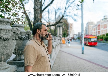Mid Adult Bearded Man Talking in the City Streets Using his Smart Phone