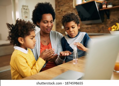 Mid Adult Black Mother And Her Kids Disinfecting Their Hands At Home.