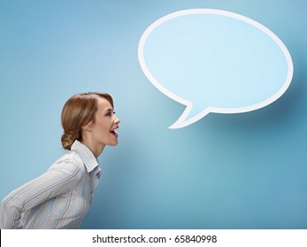 mid adult business woman screaming in blank speech bubble on blue background. Horizontal shape, side view, waist up, copy space