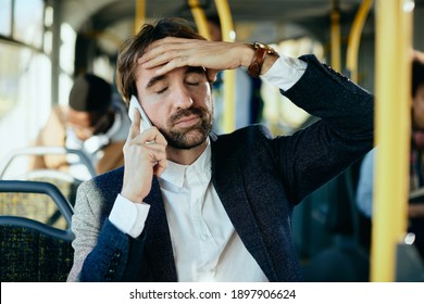 Mid adult businessman feeling displeased while talking on mobile phone and commuting by bus.  - Powered by Shutterstock