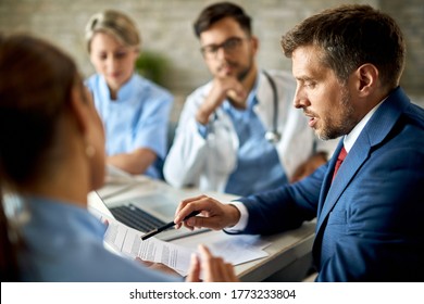 Mid Adult Businessman And Healthcare Workers Analyzing Documents During A Meeting In The Office. 