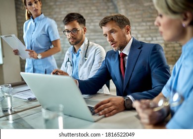 Mid Adult Businessman And Healthcare Workers Cooperating While Working On A Computer During A Meeting In The Office.