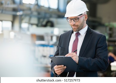 Mid adult businessman writing on clipboard in metal industry - Powered by Shutterstock