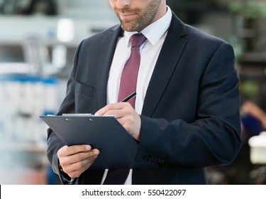 Mid adult businessman writing on clipboard in metal industry - Powered by Shutterstock