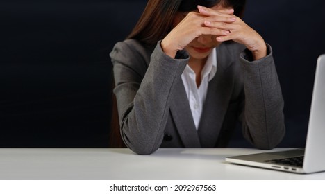 Mid adult businesswoman hands lying face down on table after bad news business failure or get fired and feeling discouraged, distraught and hopeless on blue background with computer and copy space.