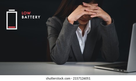 Mid adult businesswoman hands lying face down on table after bad news business failure or get fired and feeling discouraged, distraught and hopeless with low battery graphic above computer.