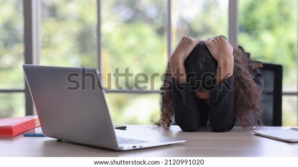 Mid adult businesswoman lying face down on table in\
office after bad news business failure or get fired and feeling\
discouraged, distraught, distraught and hopeless in modern office.\
