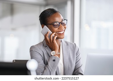 Mid adult businesswoman talking on cellphone in office. Smiling african american business woman in happy conversation on mobile phone. Mature confident black woman entrepreneur working from office. - Powered by Shutterstock