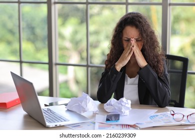 Mid adult businesswoman touching her face on table in office after bad news business failure or get fired and feeling discouraged, distraught and hopeless in modern office. 
