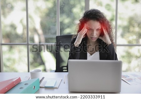 Mid adult businesswoman touching her head on table in office after bad news business failure or get fired and feeling discouraged, distraught and hopeless in modern office. 