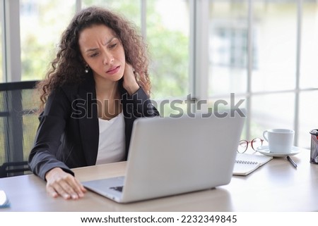 Mid adult businesswoman touching her neck on table in office after bad news business failure or get fired and feeling discouraged, distraught and hopeless in modern office. 