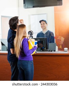 Mid Adult Couple Checking Movie Schedule On Screen At Box Office