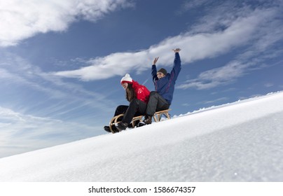 Mid Adult Couple Snow Sledding On Snow Slope