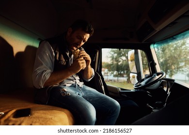 Mid Adult Driver Eating Sandwich In Truck Cabin On Parking Lot.