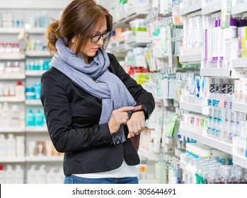 Mid adult female consumer in casuals using smartwatch in pharmacy