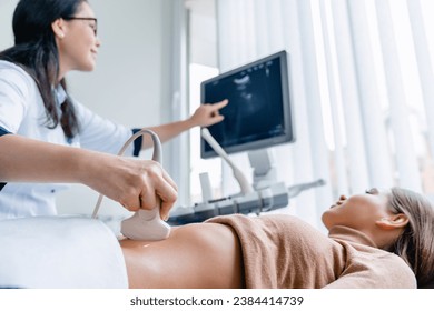 Mid adult female doctor using ultrasound scanner. Fertility pregnancy ovulation concept. Gynecologist telling and showing patient embryo. Prenatal period - Powered by Shutterstock