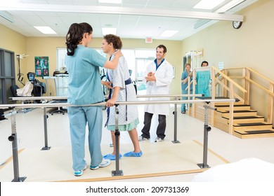 Mid adult female patient being assisted by physical therapist while doctor applauding