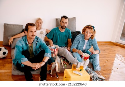 Mid Adult Friends Watching Together Sport Championship Game On TV, Drinking Beer And Eating Popcorns. Breathless Multiethnic People Looking Favorite Programme. Moment Of Silence In Anticipation