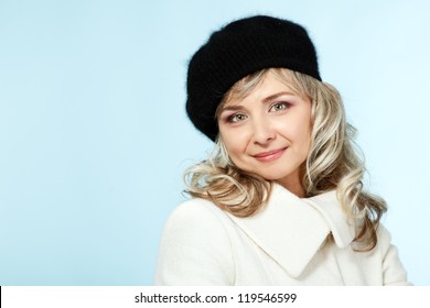 Mid Adult Happy Attractive Woman Gives A Wink, Winter Portrait Of Attractive Caucasian Middle Aged 40 Years Old Lady In Coat And Hat Over Blue