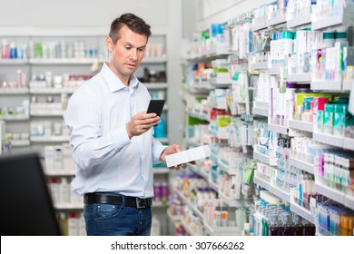 Mid adult male consumer checking information on mobile phone while holding product in pharmacy - Powered by Shutterstock