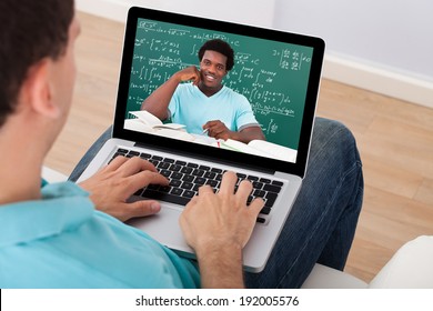 Mid adult man attending online math's lecture on laptop at home