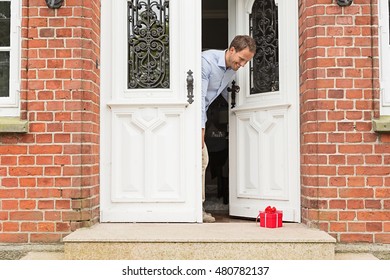 Mid Adult Man With Gift On Front Doorstep