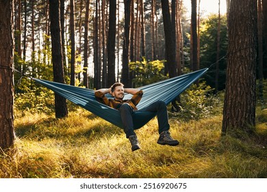 Mid adult man relaxing on hammock in the forest - Powered by Shutterstock