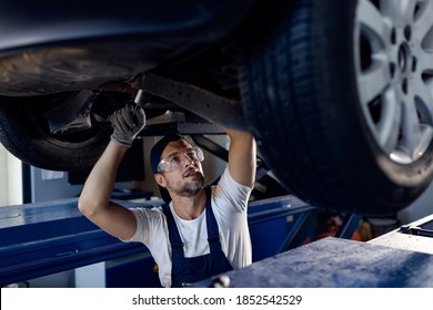 Mid Adult Mechanic Repairing Undercarriage Of A Car In Auto Repair Shop. 