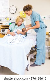 Mid adult nurse assisting woman in holding newborn baby at hospital room