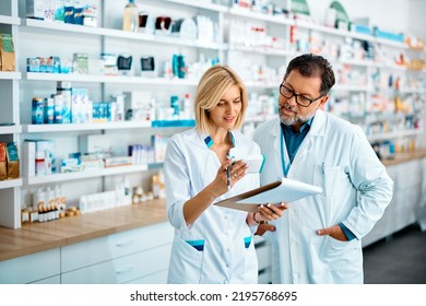 Mid adult pharmacist and her mature colleague checking inventory while working in drugstore. - Powered by Shutterstock