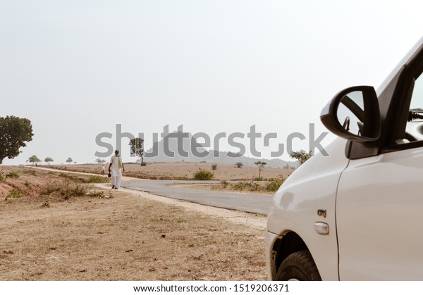 Mid adult Poor Indian village\
people walking alone in an empty road in a scorching hot summer\
day. A car point of view image. A Bihar India tourism\
photography.