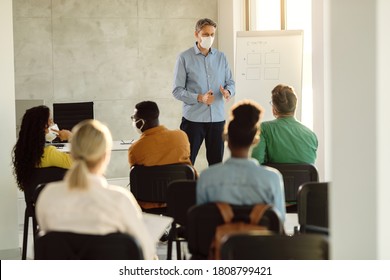 Mid Adult Professor Wearing Face Mask While Talking To A Group Of College Students In Lecture Hall. 