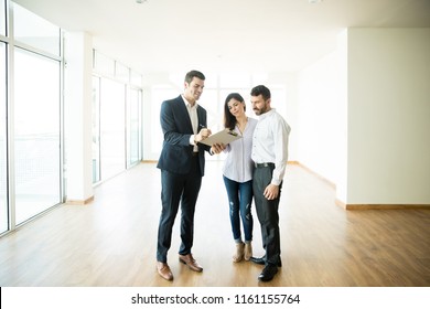 Mid adult realtor explaining agreement to couple in new apartment