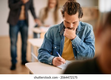 Mid Adult Student Writing An Exam At University Classroom.