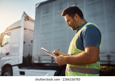 Mid Adult Truck Dispatcher Checking Shipment List On A -parking Lot.