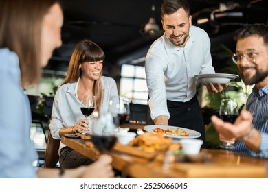 Mid adult waiter serving group of business people during lunch time in a restaurant. - Powered by Shutterstock