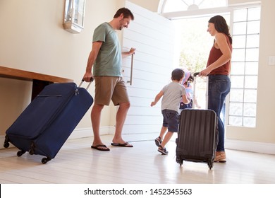 Mid Adult White Couple And Kids Leaving Their Home With Luggage To Go On Vacation, Full Length