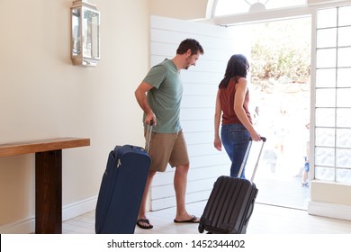 Mid adult white couple at their front door leaving home with luggage to go on vacation, full length