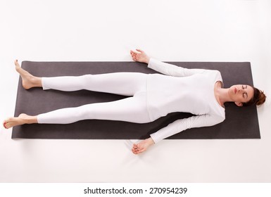 Mid Adult Woman Doing Yoga And Taking A Deep Relaxation While Lying On The Mat On The Floor