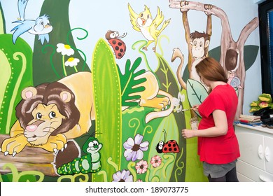 Mid adult woman drawing on the wall,mural art.Cartoon theme