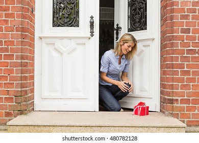 Mid Adult Woman With Gift On Front Doorstep