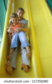 Mid Adult Woman With A Girl Sliding On A Slide