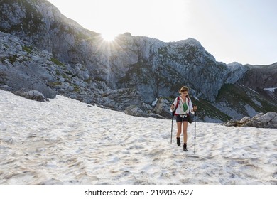 Mid Adult Woman Hiking On Snow In Springtime Mountains At Sunrise