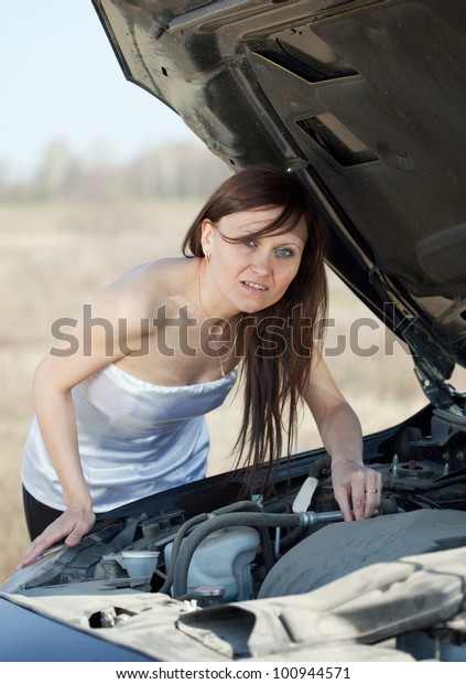 Mid adult woman\
looking under the car hood
