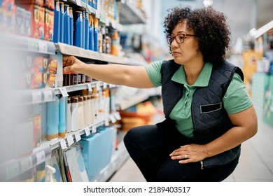 Mid adult woman organizing products on shelves while working in supermarket. 