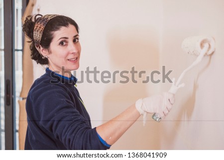 Mid adult woman paints the rooms of her house with casual clothes before the arrival of spring.