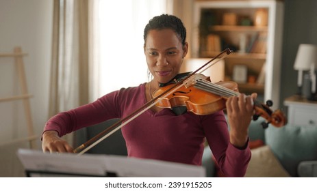 Mid adult woman playing violin at home - Powered by Shutterstock