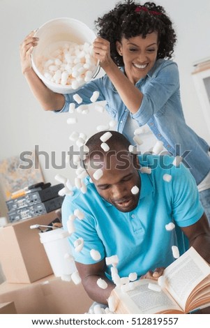 Mid adult woman pouring polystyrene over man's head